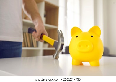 Cute Yellow Ceramic Piggy Bank About To Be Smashed With A Hammer. Man In Dire Need Of Money Is Going To Break His Piggybank On The Table. Cropped Close Up Shot. Saving Up, Or Being In Debt Concepts