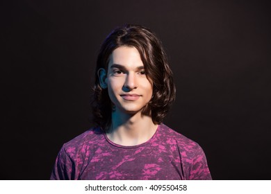 Cute Young Adult Caucasian Boy Portrait, With Long Hair. Head And Shoulders Studio Shot (colorful Gel Lights), Black Background.