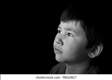 Cute Young Asian Boy Looking Up With Serious Look On Black Background In Black And White