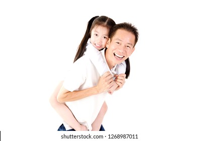 Cute Young Asian Girl On A Piggy Back Ride With Her Dad. Looking At Camera.