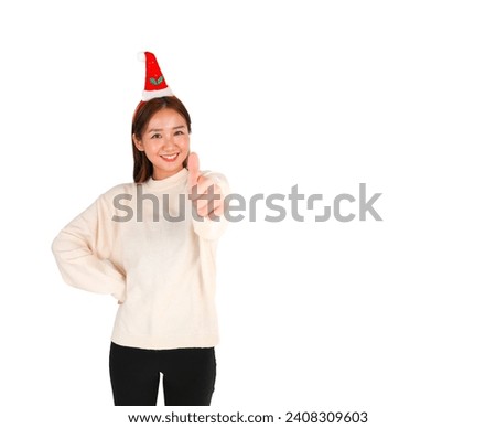Cute young asian woman doing a thumb up gesture with her hand while wearing a Christmas party hat against a white background