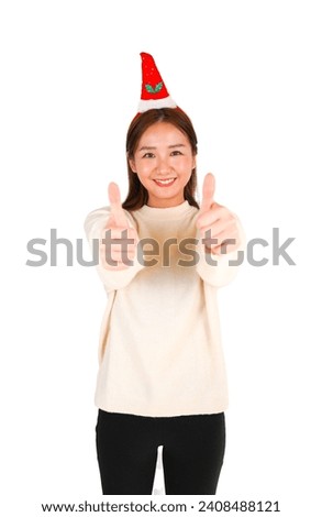 Cute young asian woman doing a thumb up gesture with both hands while wearing a party hat against a white background