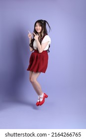 The Cute Young Asian Woman With Preppy Dressed Standing On The Purple Background.