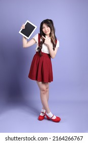 The Cute Young Asian Woman With Preppy Dressed Standing On The Purple Background.