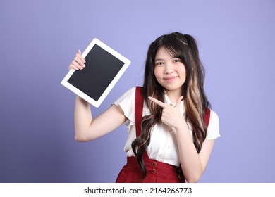 The Cute Young Asian Woman With Preppy Dressed Standing On The Purple Background.