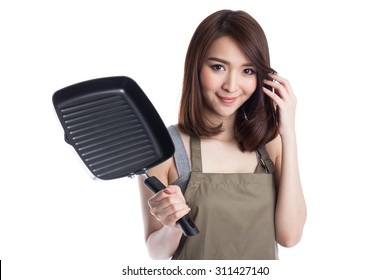 Cute young attractive asian girl wearing apron holding a teflon pan, isolated on white background