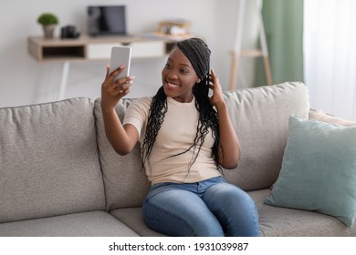 Cute Young Black Lady With Stylish Dreadlocks Taking Selfie On Smartphone For Social Media Or Friends, Positive African American Woman Having Fun At Home, Using Mobile Phone, Copy Space