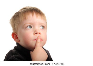 Cute young boy with blonde hair and green eyes looking up with finger on lips, wondering.