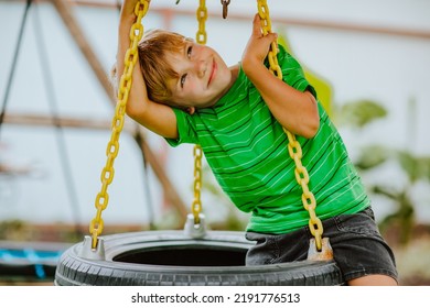 Cute Young Boy In Green Shirt And Black Shorts Is Playing On Back Yard Playground. 