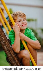 Cute Young Boy In Green Shirt And Black Shorts Is Playing On Back Yard Playground. 