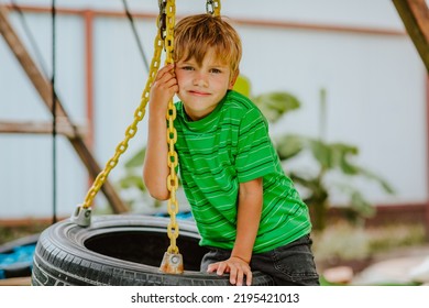 Cute Young Boy In Green Shirt And Black Shorts Is Playing On Back Yard Playground. 