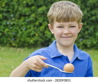 Cute young boy participating in the egg and spoon race at a traditional school sports day - Powered by Shutterstock