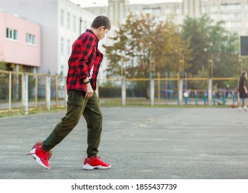 Cute Young Boy Plays Basketball On Street Playground. Teenager In Red Check Flannel Shirt With Orange Basketball Ball Outside. Hobby, Active Lifestyle, Sport Activity For Kids.