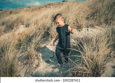 Cute young boy running on sunny sandy beach.