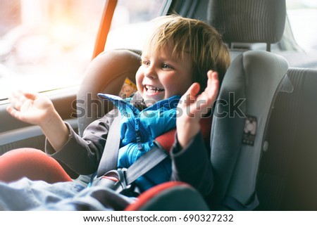 Cute young boy smiling in his car seat