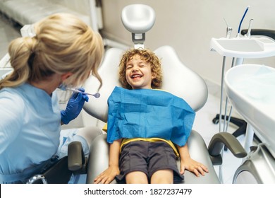 Cute young boy visiting dentist, having his teeth checked by female dentist in dental office - Powered by Shutterstock
