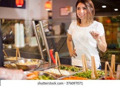 Cute Young Brunette Choosing Her Favorite Ingredients For A Salad At A Restaurant