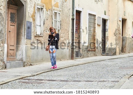 Cute young caucasian woman holding vintage retro camera on the street.