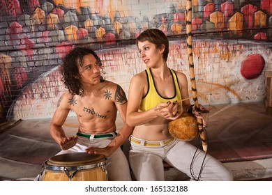 Cute young couple in capoeira outfit playing traditional instruments - Powered by Shutterstock