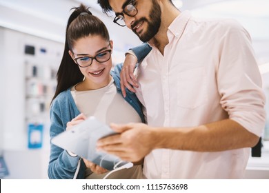 Cute Young Couple Is Checking Out A Test Tablet In A Bright Tech Store.