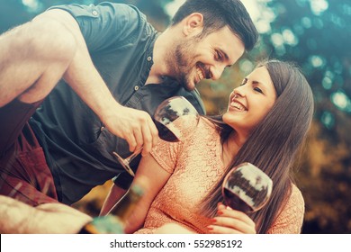 Cute Young Couple Drinking Red Wine On A Picnic In Park.