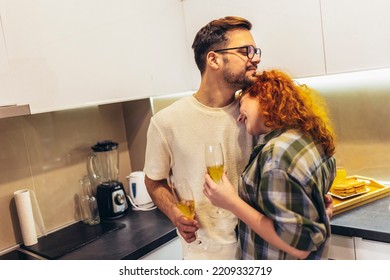 Cute Young Couple Drinking Wine In Kitchen.