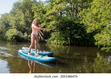 Cute Young Couple Paddle Boarding In A Beautiful River