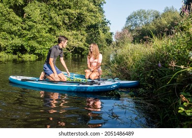 Cute Young Couple Paddle Boarding In A Beautiful River