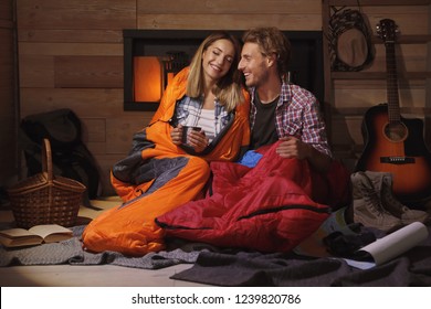 Cute Young Couple In Sleeping Bags Indoors