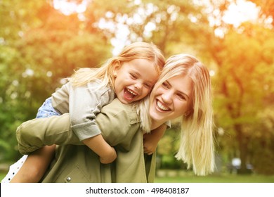 Cute young daughter on a piggy back ride with her mother. - Powered by Shutterstock