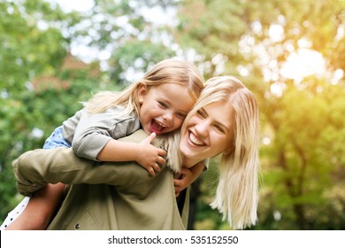 Cute young daughter on a piggy back ride with her mother. - Shutterstock ID 535152550