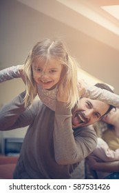 Cute Young Daughter On A Piggy Back Ride With Her Dad. Looking At Camera.