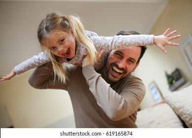 Cute Young Daughter On A Piggy Back Ride With Her Dad. Looking At Camera.