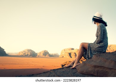 Cute Young Dreamy Woman Traveler Barefoot Sit Viewpoint Enjoy Calm Morning In Wadi Rum Desert In Jordan.Vintage Travel Carefree Holiday Tourism Concept