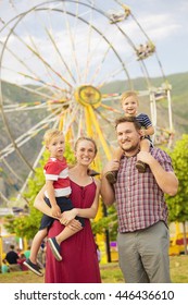 Cute Young Family Enjoying A Day At Amusement Park 