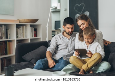 Cute Young Family Spending Time Together Using Tablet Computer At Home