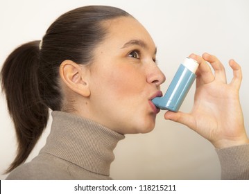 Cute young female using an asthma inhaler for preventing attacks