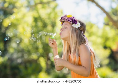 Cute young girl blowing bubbles through bubble wand in park - Powered by Shutterstock