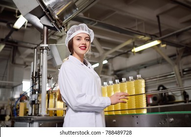 Cute young girl with a bottle of sunflower or olive oil on a production background.