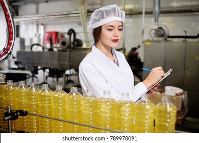 Cute young girl with a bottle of sunflower or olive oil on a production background. - Powered by Shutterstock