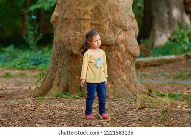 cute young girl in front of a huge old tree trunk at the botanical garden - Powered by Shutterstock