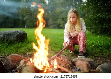 Cute Young Girl Having Fun By A Bonfire. Having Fun At A Camp Site With Family And Friends. Fun Activities In Summer.