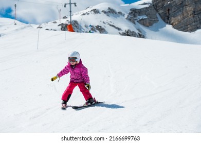 Cute young girl learning to skii at winter resort on a sunny day.