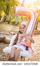 Cute Young Girl Playing With Number Seven Mylar Balloon Outdoors.