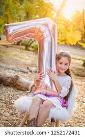 Cute Young Girl Playing With Number Seven Mylar Balloon Outdoors.