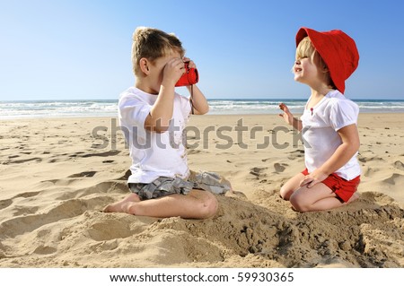 Cute young girl poses for her brother on the beach