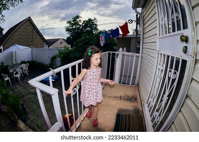 cute young girl in a summer dress playing in a suburban backyarrd