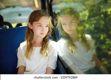 Cute Young Girl Traveling By Train On Summer Day. Child Sitting By The Window Of Railway Wagon And Looking Outside. Kid On Family Vacation In Europe.