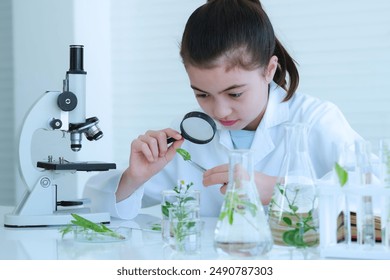 Cute young girl using magnifying glass to look at green leafy plants test samples and have many test tubes with microscope were placed on the table. - Powered by Shutterstock