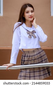 Cute And Young Girl Wearing Japanese, Korean Style Schoolgirl Uniform And Pose To Camera With Fun And Happy In Front Of School Building.